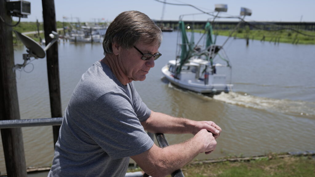 Don Beshel on the balcony of his marina Don Beshel on the balcony of his marina near Point á la Hache, as a shrimp boat leaves one morning in April 2022. Beshel’s Marina is near Mardi Gras Pass, a breach in the Mississippi River levee that occurred naturally in 2011.